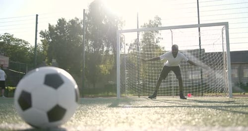 Primer plano de la pelota en el campo mientras el hombre está de pie en la red de fútbol