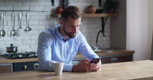 Man Using Smartphone at Modern Kitchen Counter