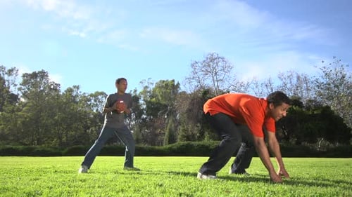 Man and Boy Playing Football in the Park