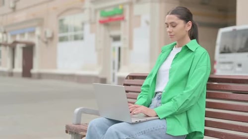 Woman Works on Laptop on Park Bench
