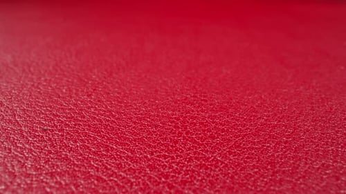 Abstraktes Muster von Falten auf roter Kuhlederoberfläche