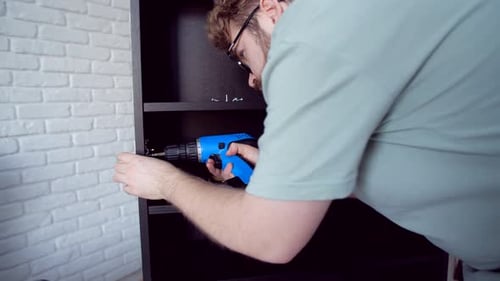 Adult Assembling Furniture With a Drill Indoors