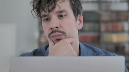 Close Up of Pensive Man Thinking While Working on Laptop
