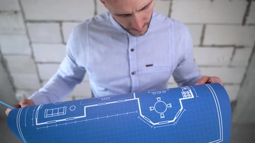 Construction engineer examines the blueprints of the building