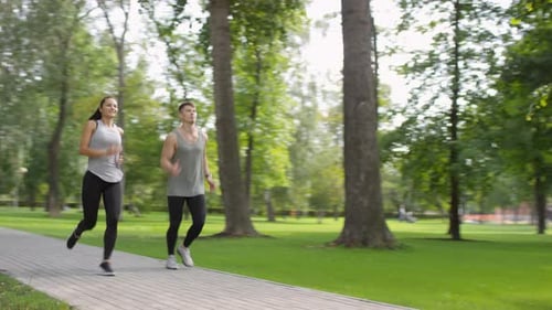 Cheerful Caucasian Couple Jogging in Park on Summer Day