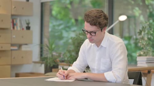 Junger Mann schreibt im modernen Büro auf Papier