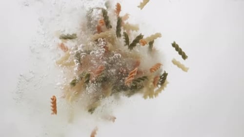 Colorful Rotini Pasta Falling into Water