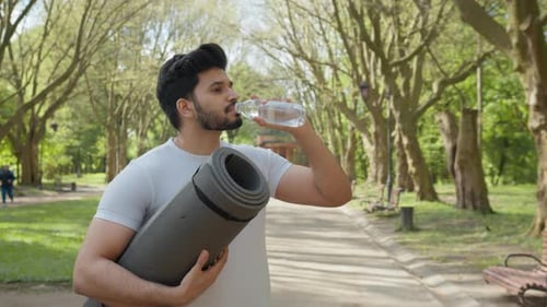 Side View of Arabian Bearded Man Wearing Sport Clothes Drinking Fresh Water From