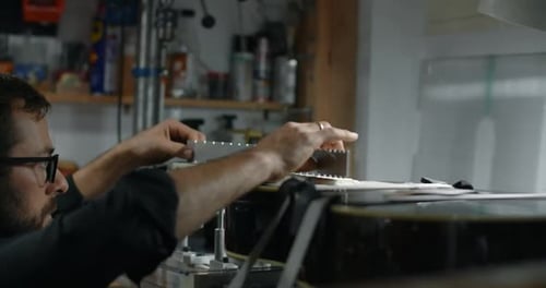 Luthier ajuste l'angle du manche de la guitare électrique montée sur le gabarit pour réparer la comédie musicale