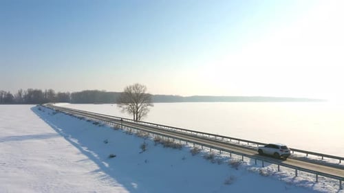 Aerial Shot of Car Riding Through Snow Covered Road Near Frozen Lake