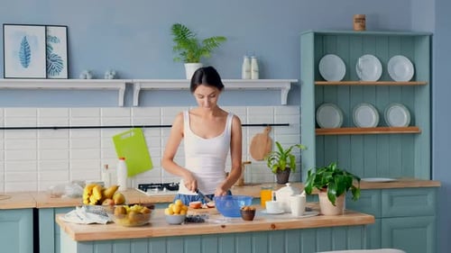 Young Woman Preparing Healthy Fruit Salad in Kitchen