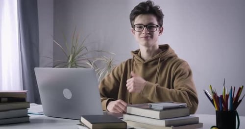 Smart Caucasian Boy Showing Thumb Up and Smiling at Camera. Portrait of Intelligent Male College