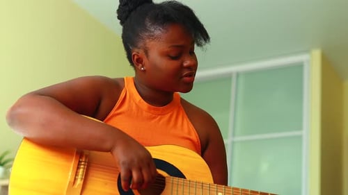Woman Plays Acoustic Guitar and Sings Indoors