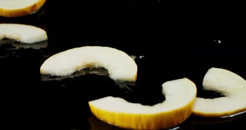 Des tranches de melon tombent sur les éclaboussures d'eau.