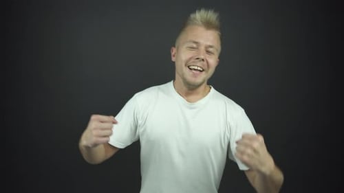 Excited Guy in White T-shirt Raises Hands with Happiness