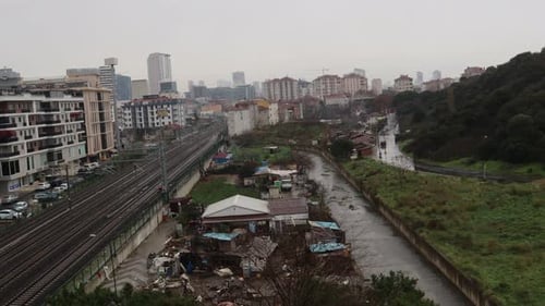 Trains circulant sur la voie ferrée le long des bidonvilles et des immeubles d'appartements près du ruisseau dans le district de Maltepe