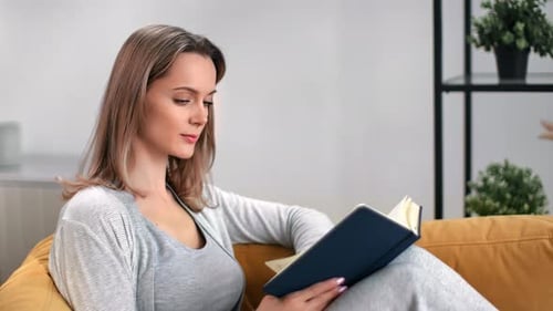 Woman Reading a Book on Couch at Home