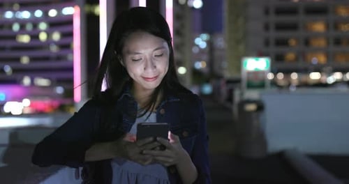 Woman Using Smart Phone in Bright Urban Night