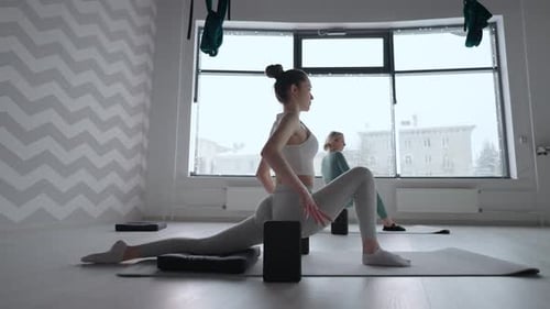 Group of Young Women Stretching in Gym with Windows