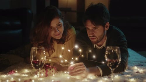 Young Couple Lying on Rug with Fairy Lights