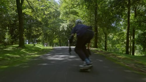 Skateboarder Skating on Asphalt Path in Park