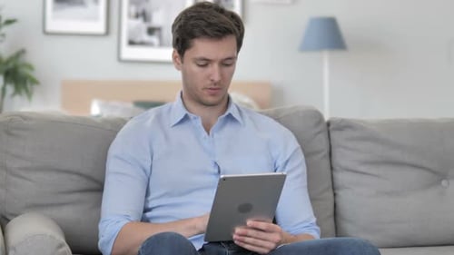 Young Adult Using Tablet on Couch at Home