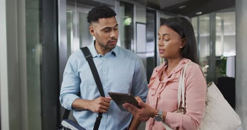 Man and Woman Discuss Tablet in Modern Office