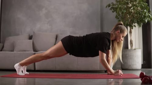 Junge, fitte und straffere Frau beim Fitnesstraining, beim Plankenwechsel die Ellbogen für einen gesunden Lebensstil