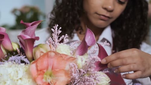 Fleuriste finissant la composition florale en atelier