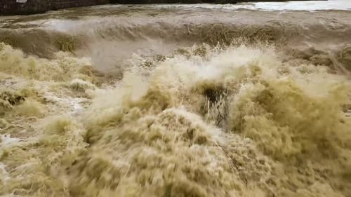 Luftaufnahme des schmutzigen Flusses mit schlammigem Wasser in der Überschwemmungszeit bei starken Regenfällen im Frühjahr.