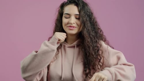 Woman Dancing Happily with Curly Hair on Pink Background