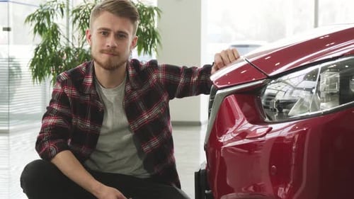 Man Smiles Holding New Car Keys in Dealership