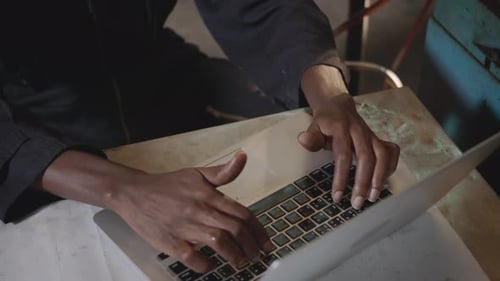 Arbeiter mit gelbem Helm und Gehörschutz Tipptastatur des Laptops