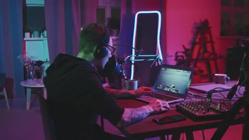 Young Adult Gaming at Computer in Neon Lit Room