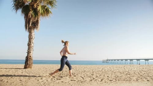 Young Woman Runs on a Sea Coast in the Morning