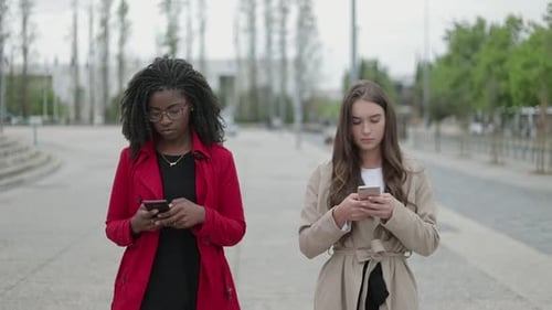 Young Women Using Phones in Urban Environment