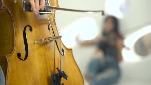 Cellist Performing with Violinist in the Background