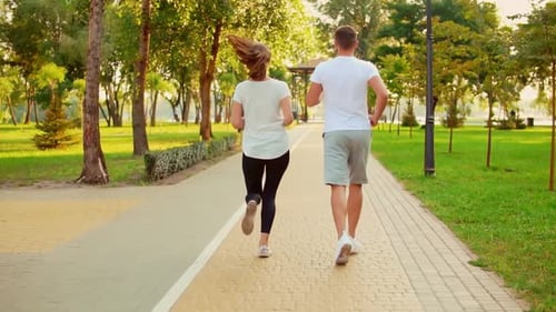 Couple Jogging Together in a Green Urban Park