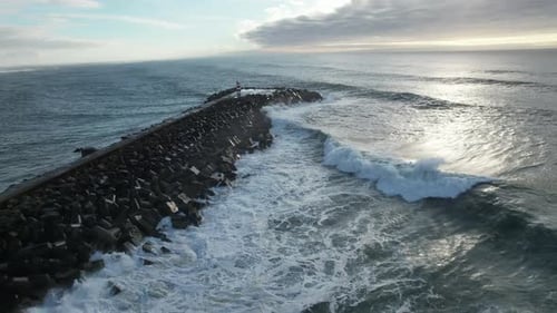 Waves Crashing on Rocky Pier with Lighthouse