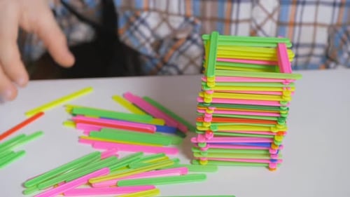 Niño construye una pirámide de palos de colores