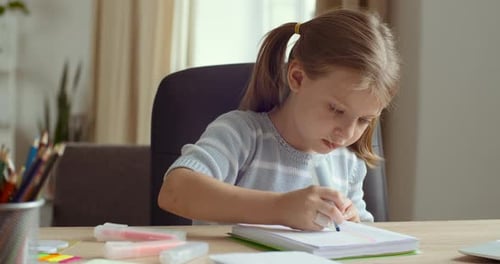 Girl Drawing in Notebook at Desk