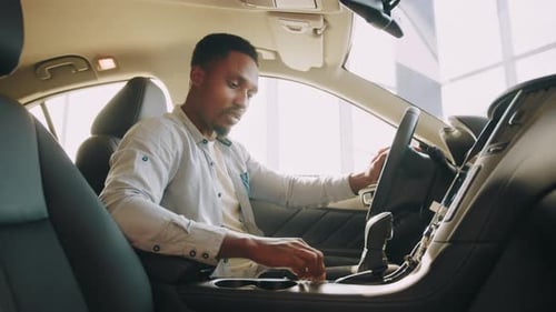 Side View of Focused African Man Sitting on Driver's Seat and Using Dashboard
