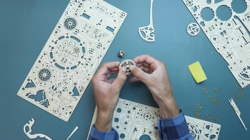 Homme assemblant les détails du volant d'un jouet mécanique en bois