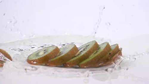 Kiwi Slices Splashing in Water on White