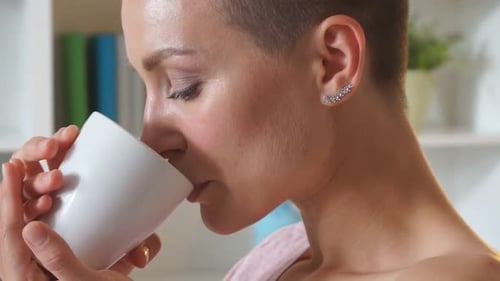 Woman Drinks from a White Cup Indoors