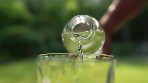 Clear Liquid Pouring Into Glass Cup Outdoors