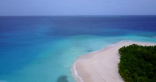 Wide fly over travel shot of a paradise sunny white sand beach and aqua blue ocean background