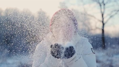 Happy Woman Blowing Snow in Winter Forest