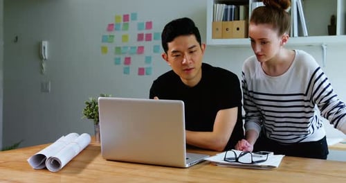 Man and Woman Discussing Project at a Laptop