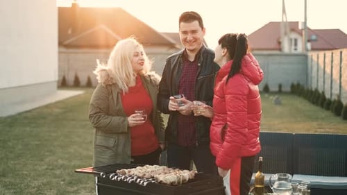 Adults Chatting Around Grill in Suburban Backyard